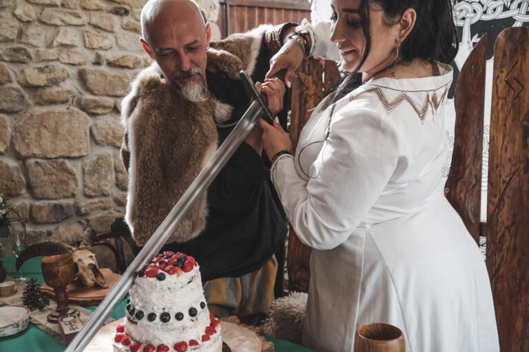 nevesta a ženích krájajú svadobnú tortu mečom 